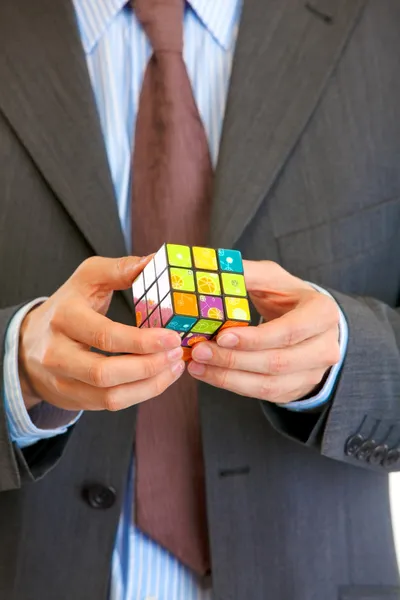 Businessman holding Rubiks cube in hand. Close up.
