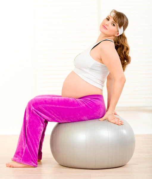Pregnant female doing pilates exercises on gray ball