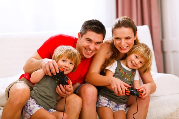 Mom and dad playing with twins daughter on console