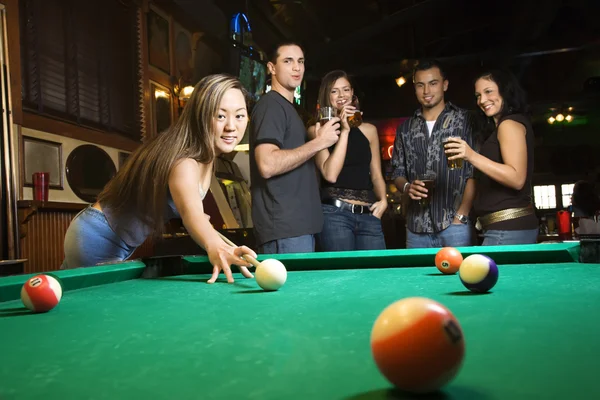 Young female preparing to hit pool ball.
