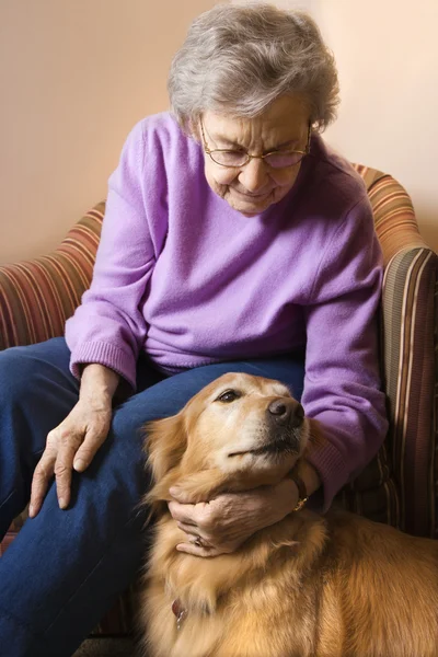 Mature woman petting dog.