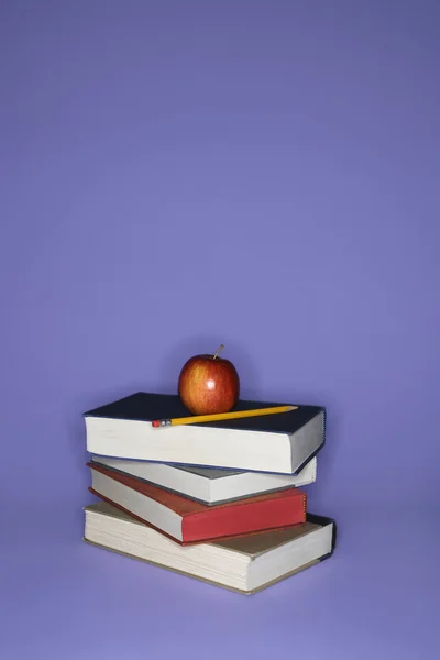 Books with apple and pencil.