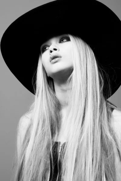 Blond woman with long beautiful hair and smoky eyes in a hat. St