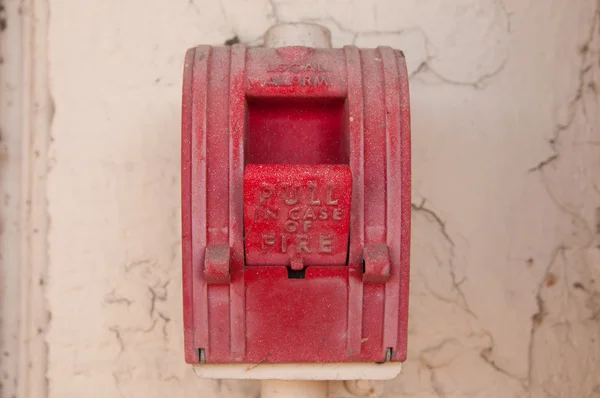 Vintage red wall fire alarm on stucco wall