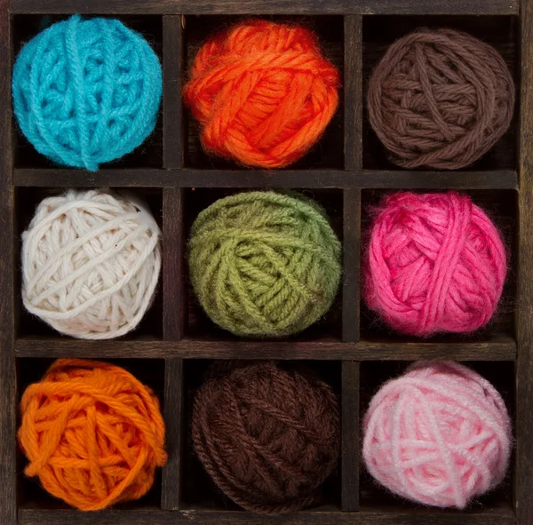 Nine colorful balls of yarn in printers box