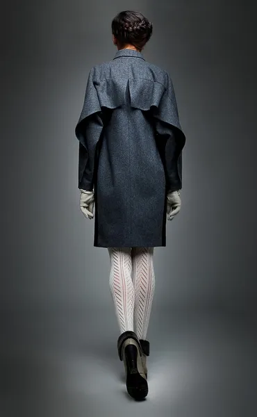 Brunette fashion model in grey coat backwards view