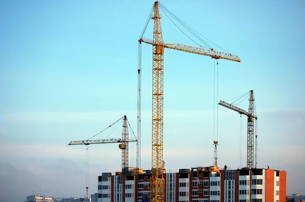 Three cranes on top of high-rise building