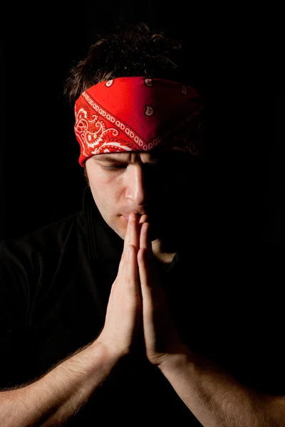 Emotional portrait of a young man praying in the darkness