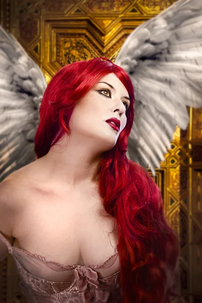 Beautiful gothic sexy angel with wings, red hair over gold backg