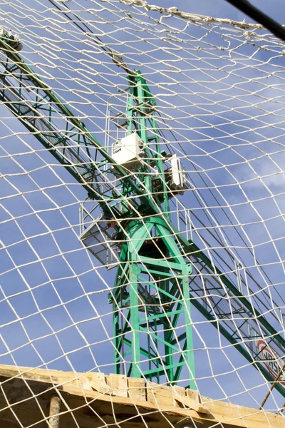 Industrial Crane behind safety net, under construction building,