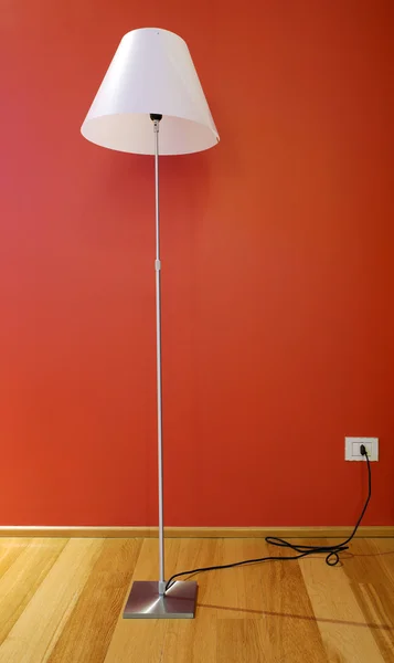 Lamp in hotel room, wooden floor and red wall