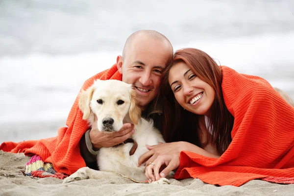 Romantic couple with a dog having fun on the beach