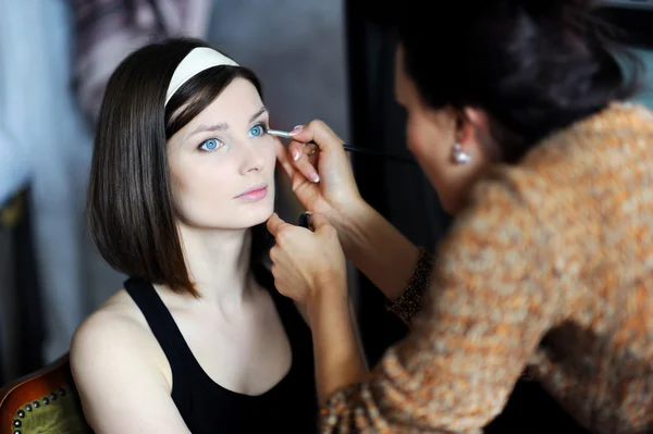 Young beautiful bride applying wedding make-up by professional m