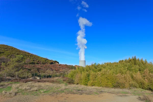 Geothermal energy. Cooling tower in a green valley.