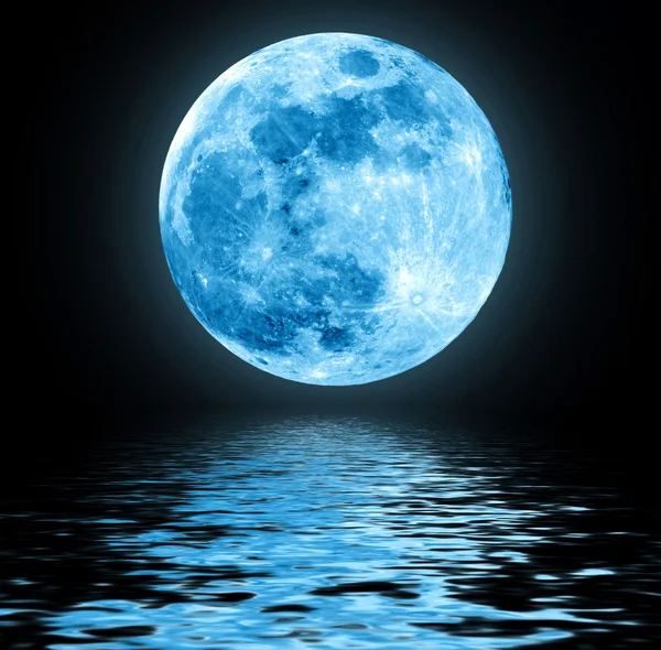 Full blue moon over water with reflections