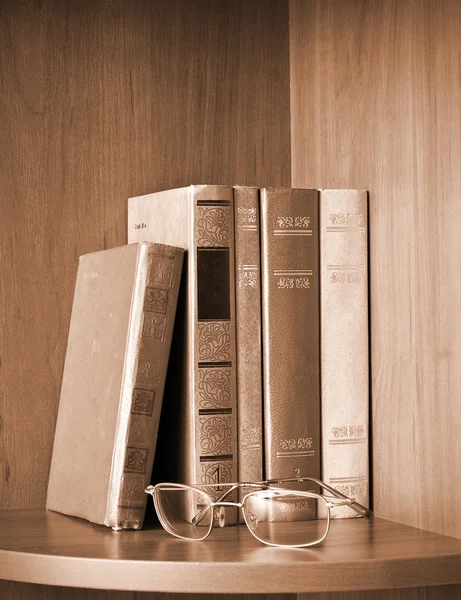 Vintage photo of old books and glasses on a shelf