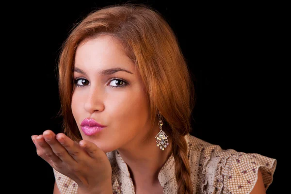 Pretty young caucasian girl sending kiss, with golden reflexion, isolated on black, studio shot