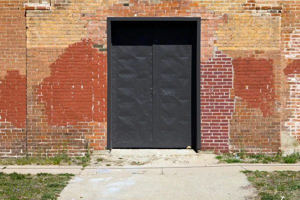 Metal Door In Old Brick Urban Building With Sidewalk