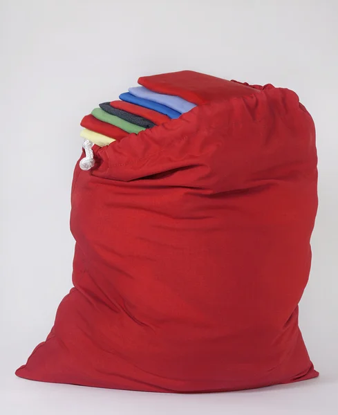Red Laundry Bag with Brightly Colored Folded Shirts Laying on Top of Each Other