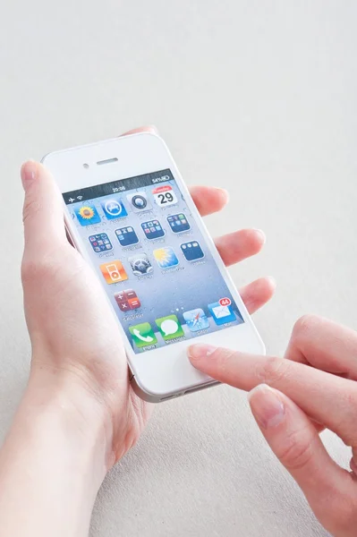 female hands with a manicure keeps white iphone 4 on a white