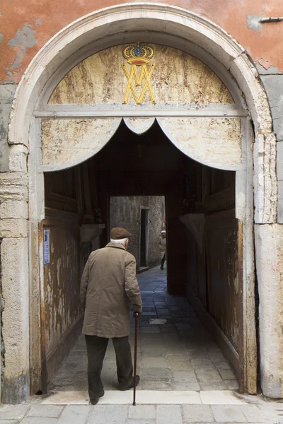 Man walking under a door with a religious inscription