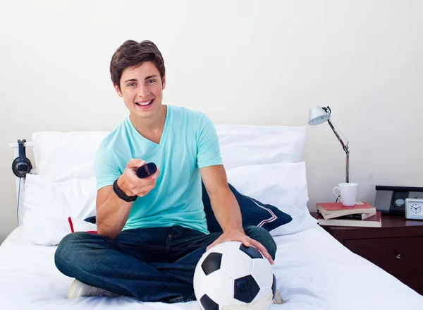 Teen guy watching a football match in television