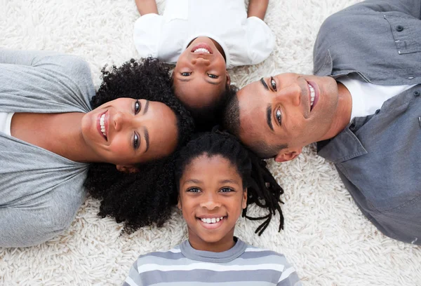 Smiling Afro-American young family lying on floor