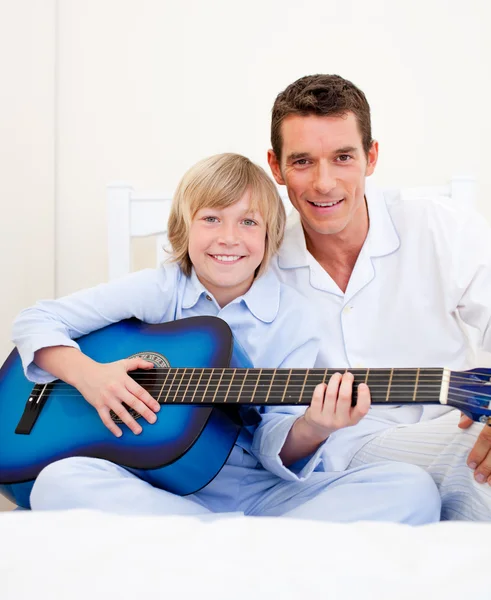 Merry little boy playing guitar with his father