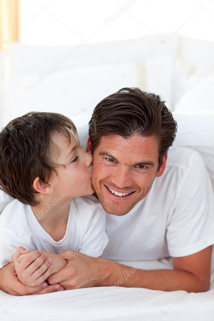 Little boy kissing his father lying on bed — Stock Photo ...