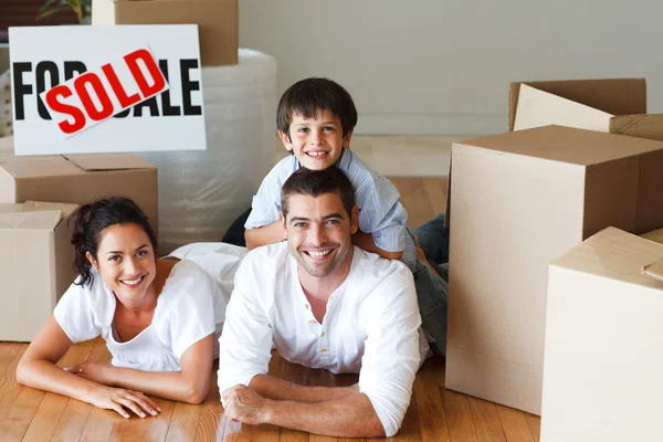 Happy parents and son lying on the floor after buying house