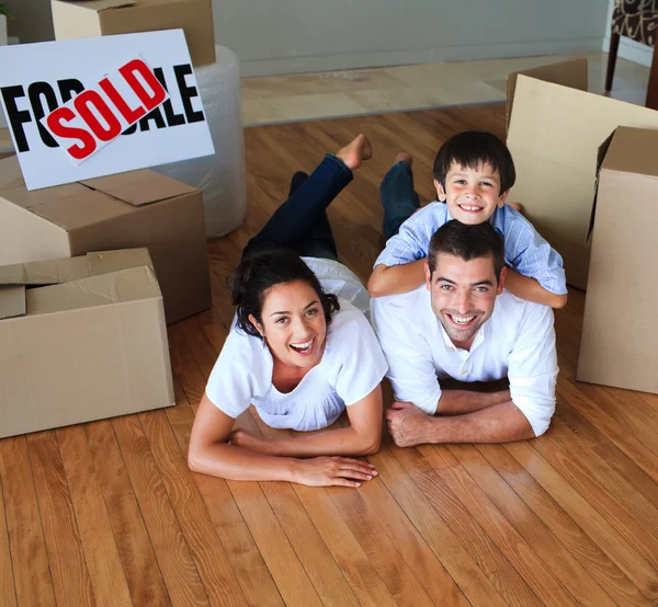 Family moving house on floor smiling at the camera