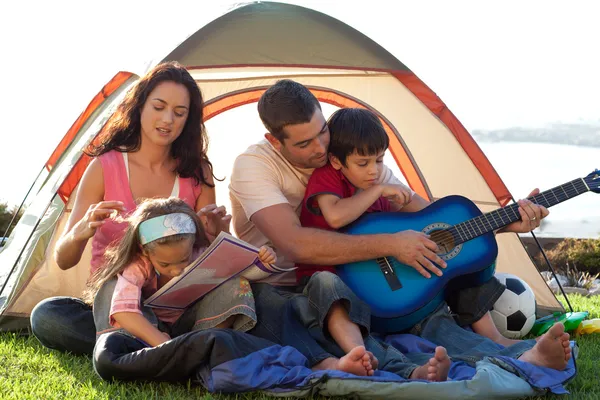 Family playing a guitar in a tent