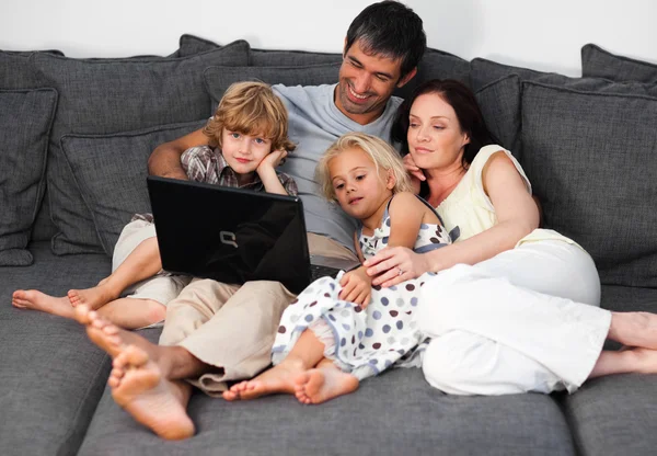 Smiling family using a laptop on a sofa
