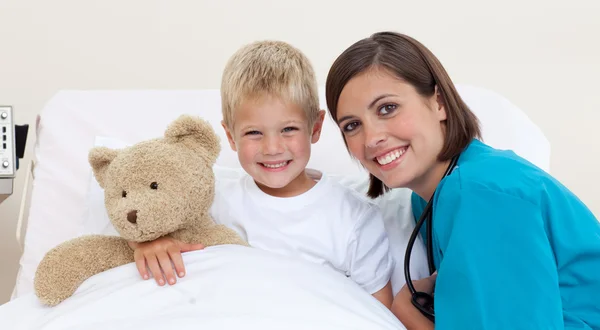 Smiling little boy and his doctor playing with a teddy bear