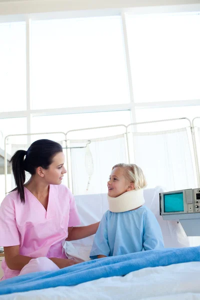 Little girl with a neck brace smiling at the nurse