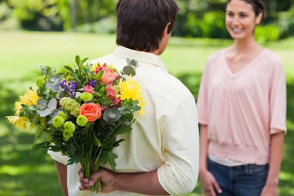 Man about to present a bouquet of flowers to his friend