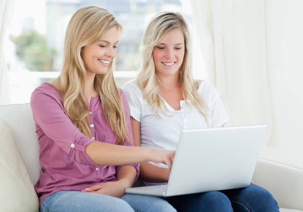 Two smiling women using a laptop as one points to the screen