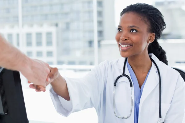 Female doctor shaking a hand