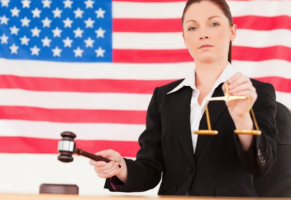 Close up of a cute judge knocking a gavel and holding scales of