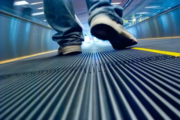 Foot walking in airport escalator perspective view (ground level)