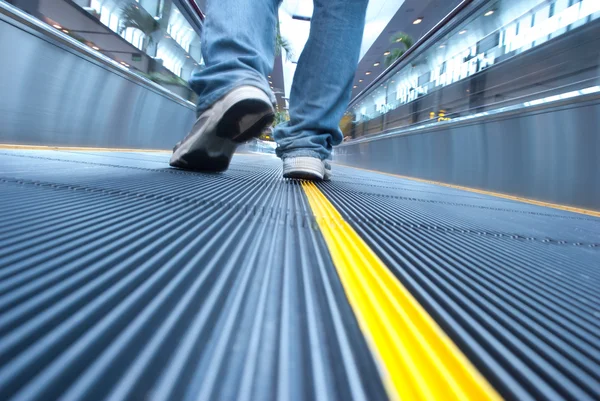 Man walking in airport escalator perspective view (ground level)
