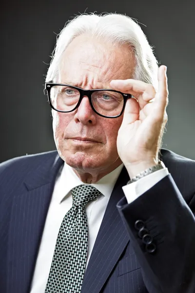 Senior business man with vintage glasses wearing dark blue suit and tie