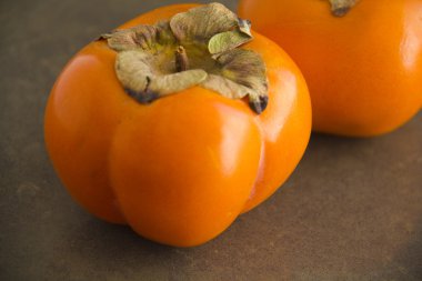 Rape persimmons on brawn background clipart