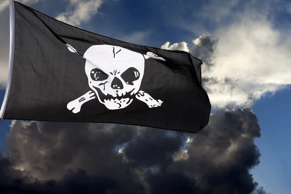 stock image Jolly Roger (pirate flag) against storm clouds