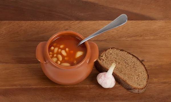 Soup in clay pot with bread and garlic — Stock Photo, Image