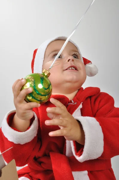 Weihnachtsmann-Baby spielt mit Weihnachtskugel — Stockfoto