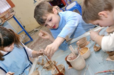 Group of hildren shaping clay in pottery studio clipart