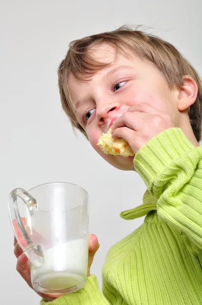 Kind isst Kuchen und trinkt Milch — Stockfoto