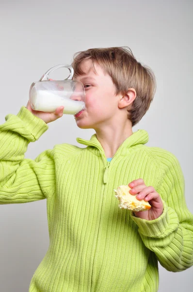 Junge isst Kuchen und trinkt Milch — Stockfoto