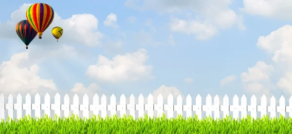 Lado del campo con hierba de valla blanca y cielo azul — Foto de Stock